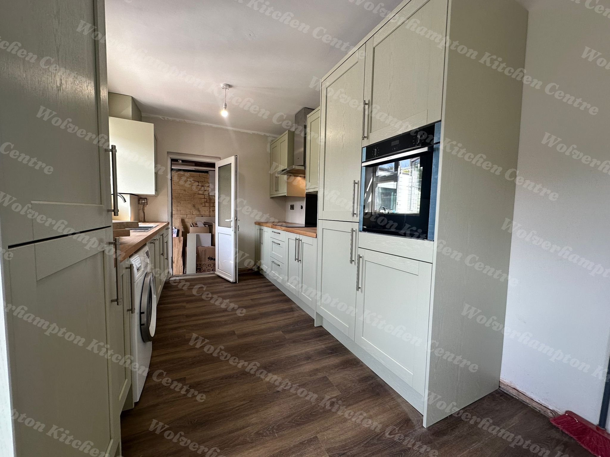 Sage green shaker kitchen with solid oak worktops and deep bowl sink installed by WKCC